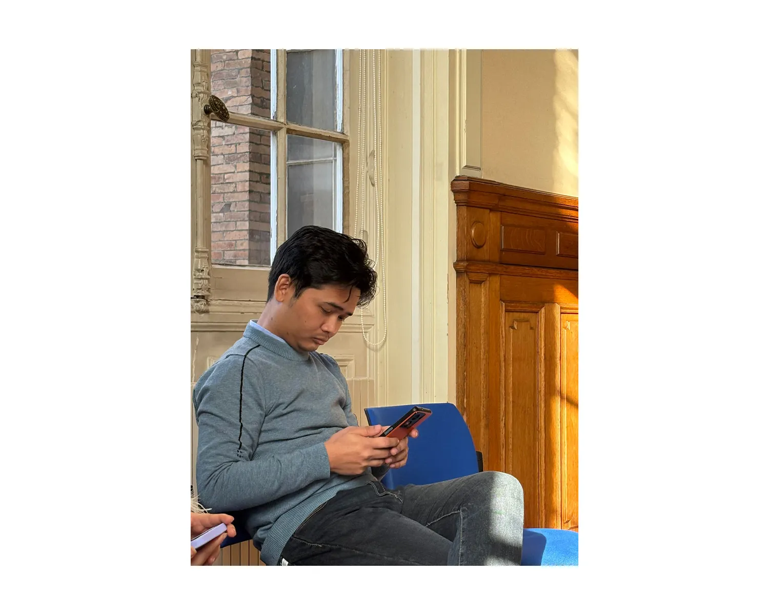Candid portrait on campus, checking a phone in the sunlight