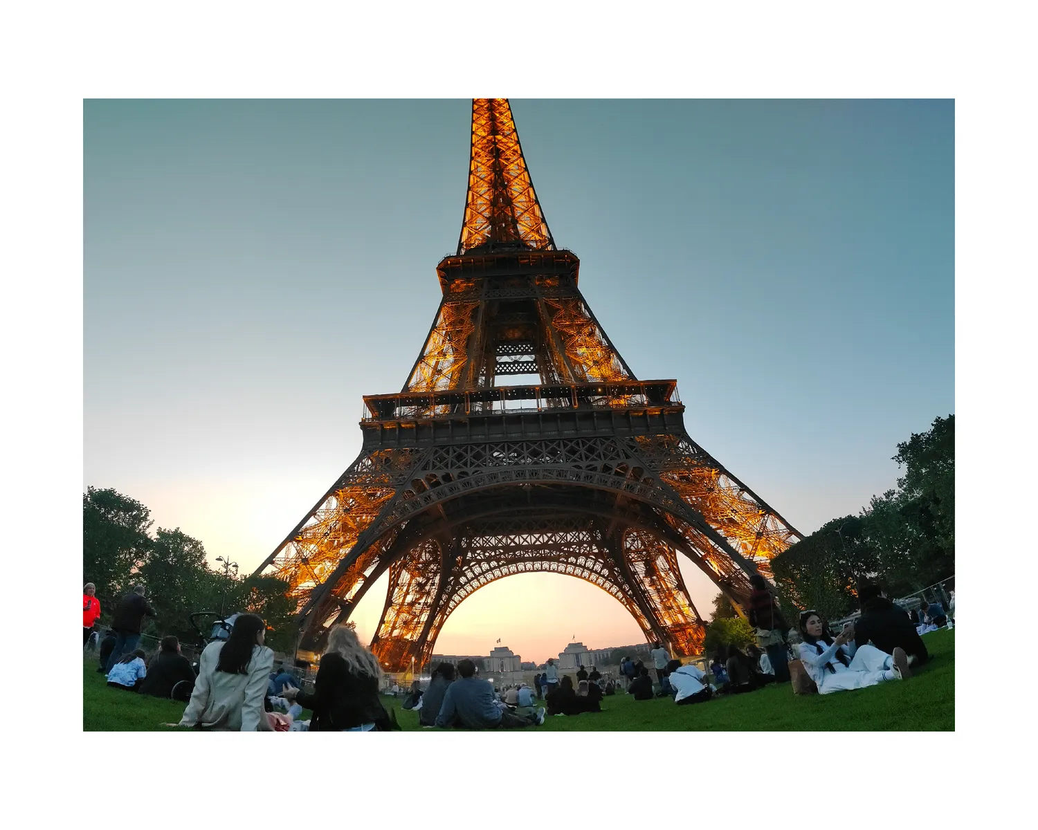The Eiffel Tower at sunset with a crowd on the Champ de Mars